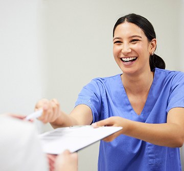 Orthodontic assistant smiling while handing parent forms