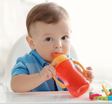 Infant boy chewing on a sippy cup