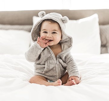 Smiling baby sitting on bed
