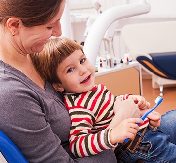 Mother in dental chair holding child in her lap