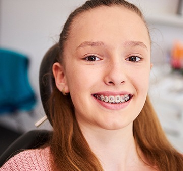 Teen with braces smiling while sitting in treatment chair