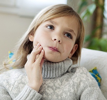 Child holding her cheek