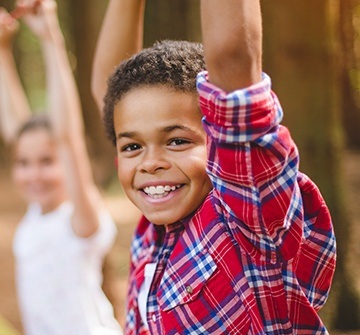 Smiling little boy with his hand up