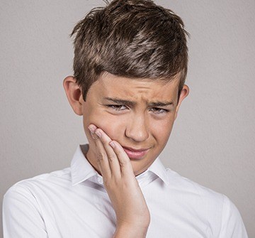Young boy holding cheek in pain