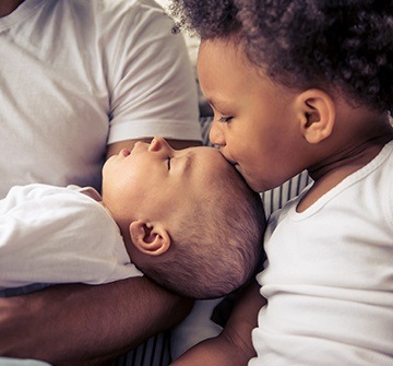 Older sibbling kissing baby on forehead