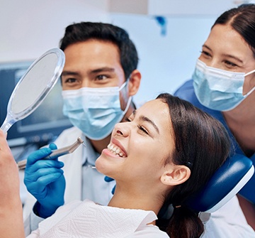 Dentist, dental assistant, and patient smiling in treatment room