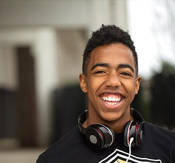 teen smiling with headphones around their neck