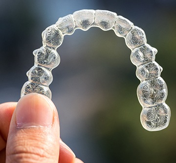 person holding Invisalign aligners