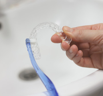 Patient cleaning clear aligner with toothbrush