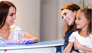 Mother and daughter at dental reception desk