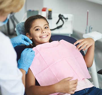 Child smiling with pink bib during dental checkup