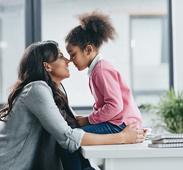 Mom and daughter touching noses on desk at home