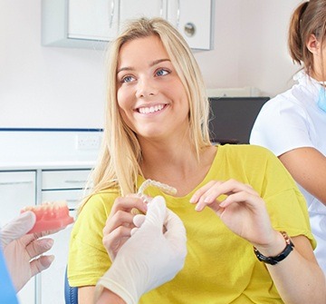 Woman in dental chair holding clear aligner