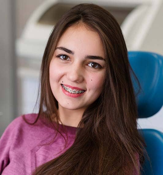Smiling teen girl with braces in dental chair