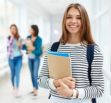Student smiling while holding books