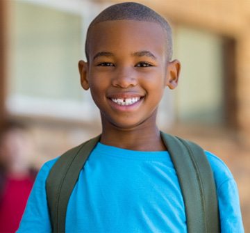 Child in blue shirt smiling at school