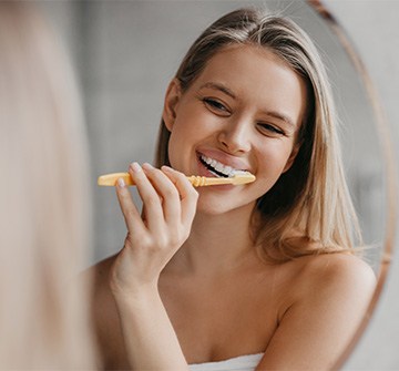 Woman smiling while brushing her teeth