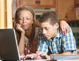 teenager and parent doing research on a laptop