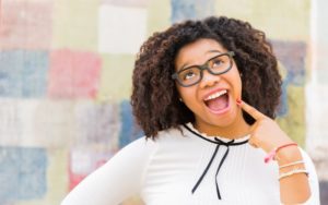 Girl pointing at her smile after visiting pediatric dentist for teens