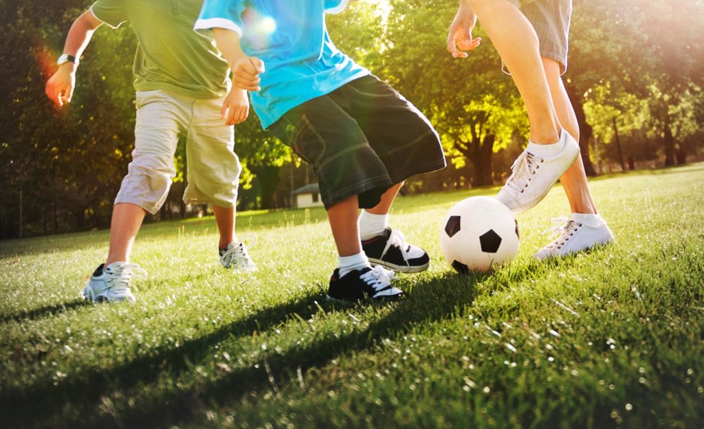 Children playing soccer at park on summer day