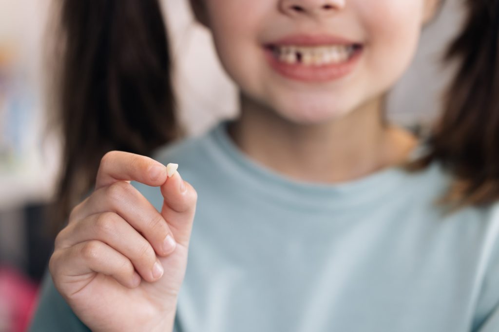 Closeup of child smiling while holding tooth