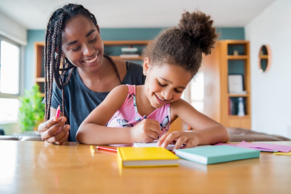 Mother and child smiling while working on homework