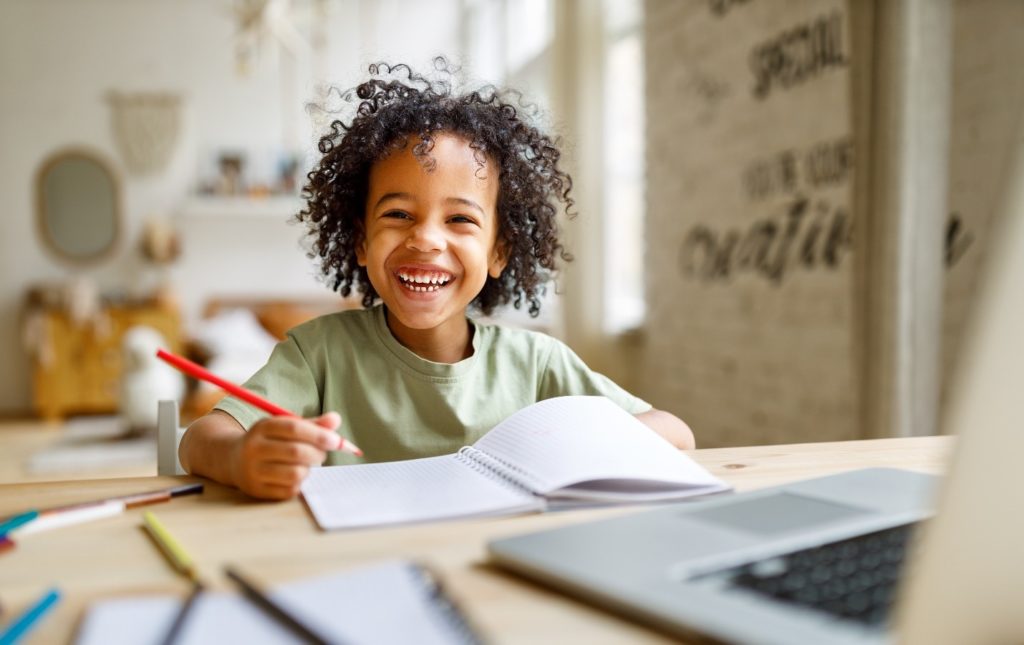 Young child smiling while coloring at home
