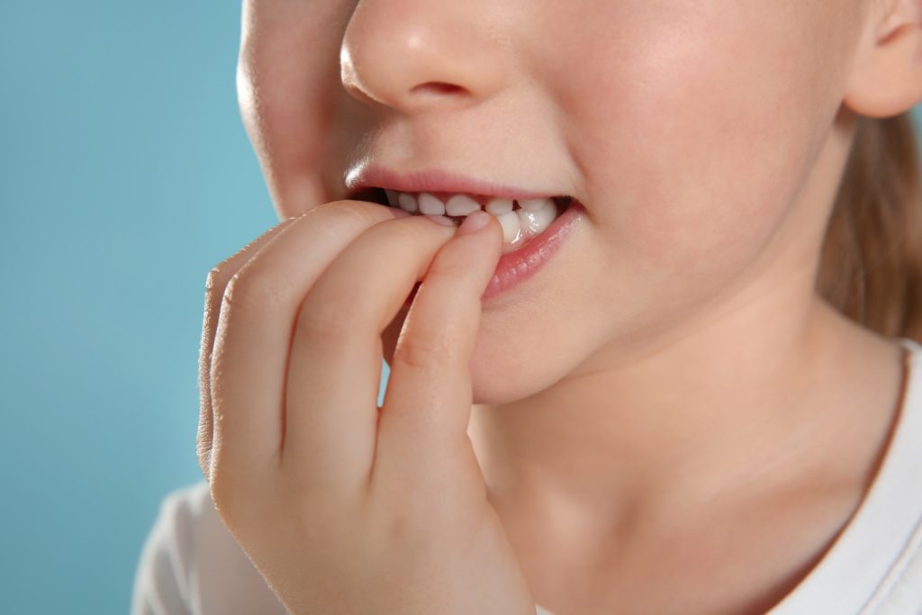 Closeup of young girl biting her nails