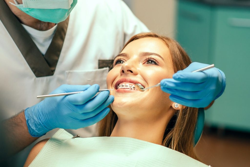 Woman with braces smiling while sitting in treatment chair